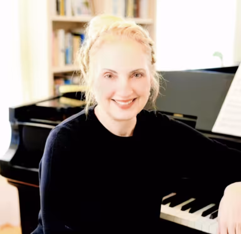 Pia Muse lächelt am Klavier – Gründerin der Pianolla®-Methode.